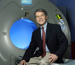 A doctor sitting next to a CT scanner