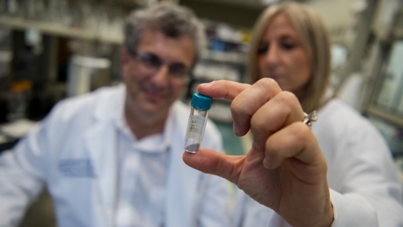 Scientists hold up vial