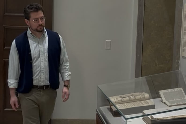 Michael Seminar walking through an exhibit room with cases of manuscripts