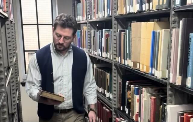 Photo of Michael Seminara walking through library stacks