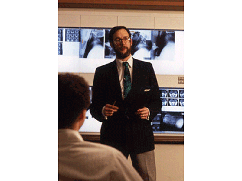 A faculty member lectures from the front of the classroom.