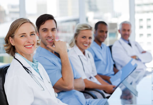 Providers sitting on bench looking into camera