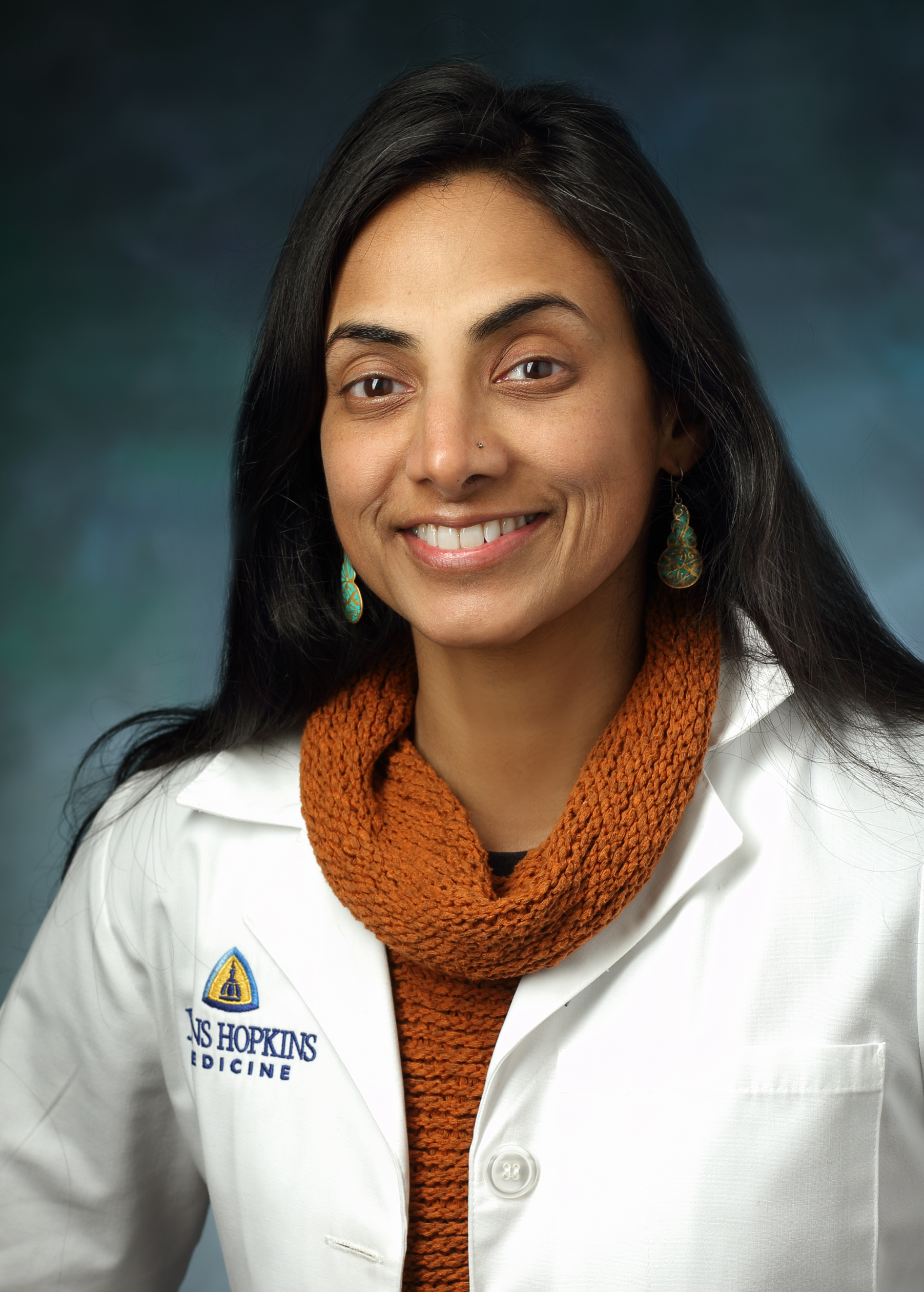 Sophia Purekal headshot. She is wearing a white coat over an orange turtleneck.