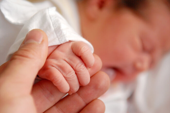 Infant holding an adult's finger