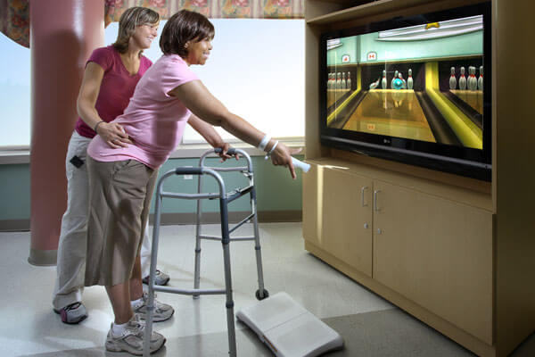 Female stroke rehab patient playing Wii bowling with a rehab therapist