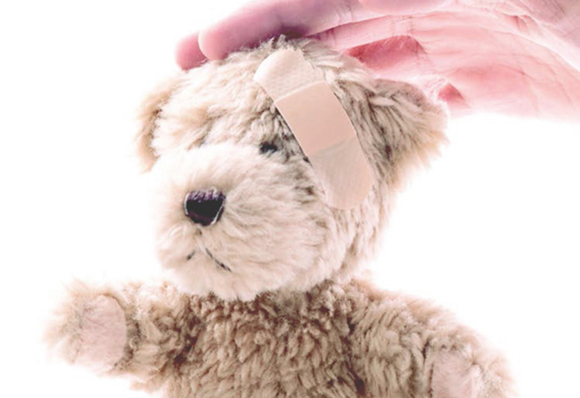 A teddy bear has a bandage on its head