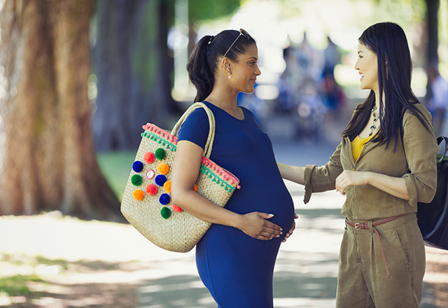 A pregnant woman speaks with a friend