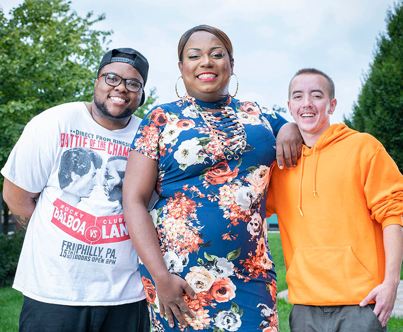 three transgender patients pose outside together, smiling
