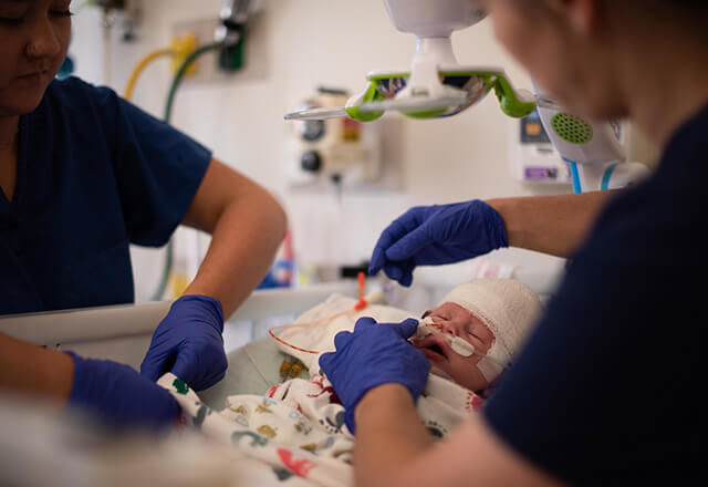 two medical professional working with an infant