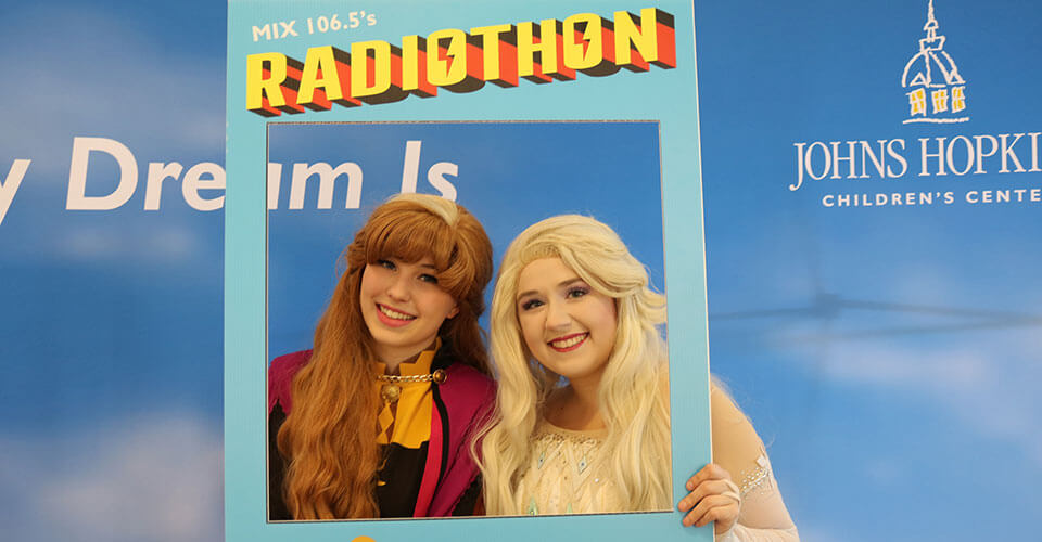 anna and elsa holding a radiothon sign