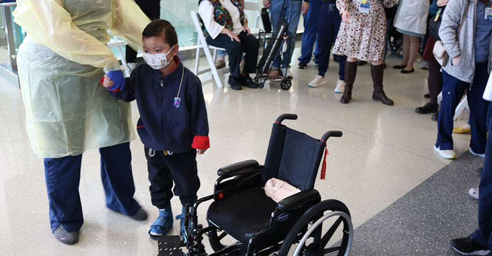matthew standing next to his wheelchair