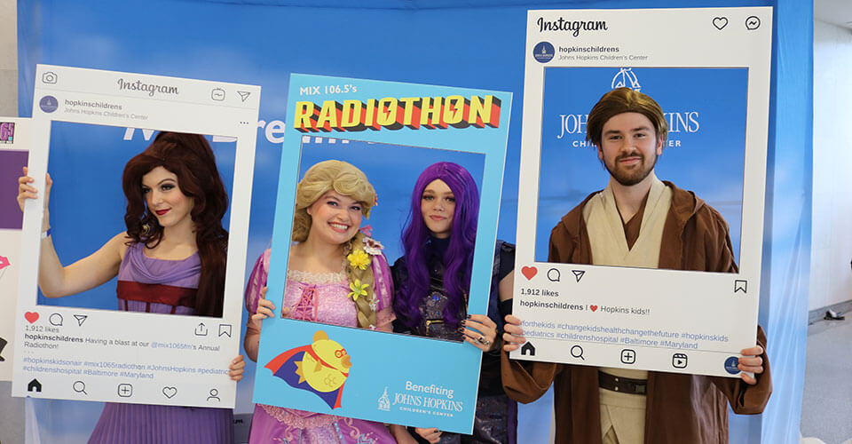 meg, obi wan, mal, and rapunzel holding radiothon signs