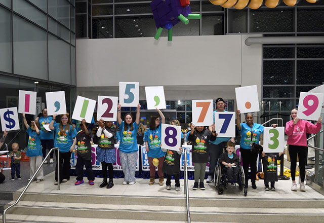 Radiothon families hold up the numbers of the raised amount from the 2025 event