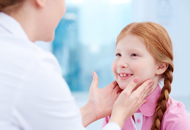pediatrician checks glands on the neck of a child for swelling