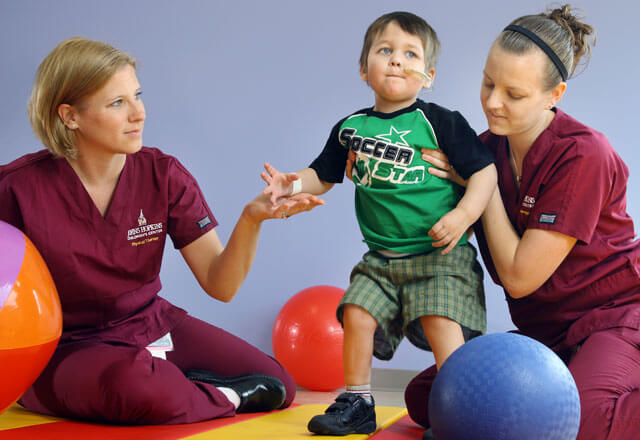 Nurses help a child with physical and occupational therapy
