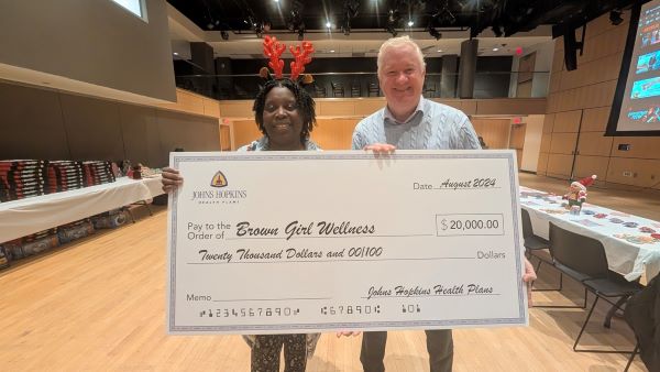 Dr. D. Rica Wilson and Doug Hemmig holding a giant check at their company holiday event.
