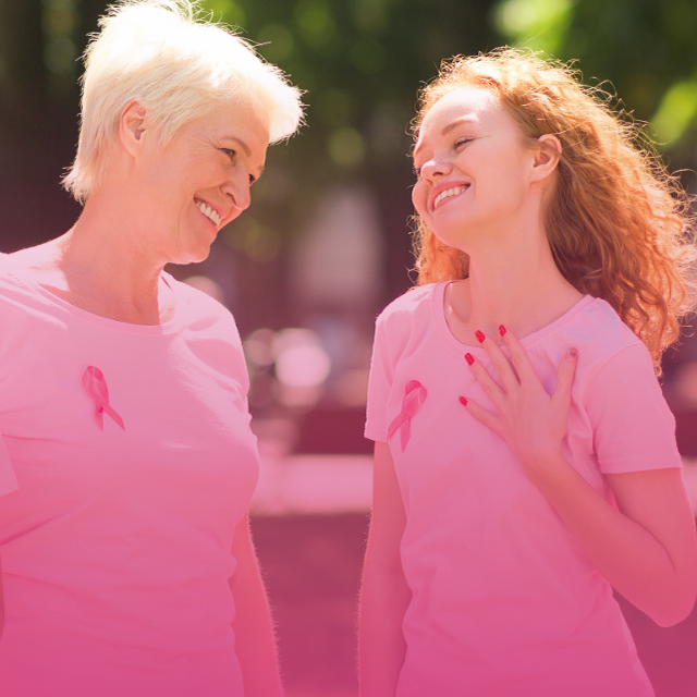 Image of an older woman and a younger woman smiling, both wearing pink shirts