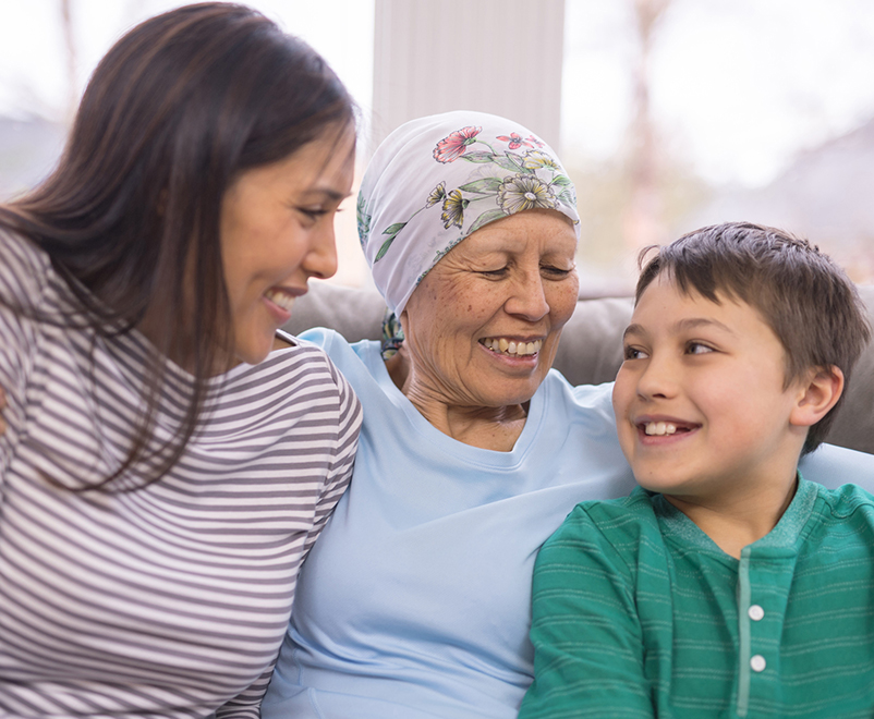 stomach cancer treatment - mature woman wearing scarf with grandchildren