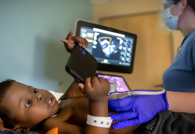 A child looking at a movile device during an ultrasound 
