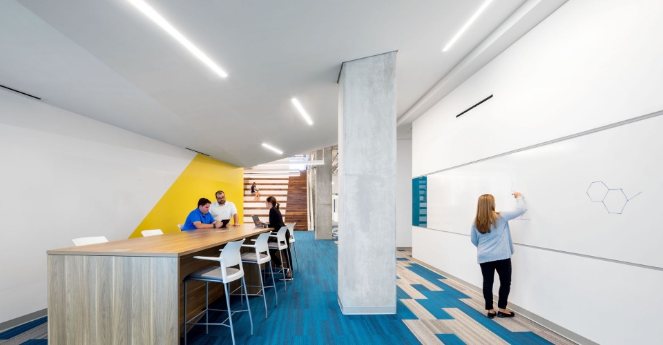 A view of the Research and Education Building's second level common area with two women sitting on a bench conversating.