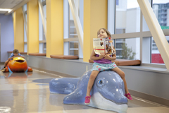 A girl sitting on a model dolphin in Johns Hopkins All Children's Hospital