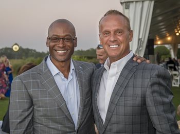 Two men in suits smiling at the JHACH Golf Invitational event