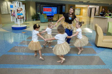 Chloe, 4, McKinley, 4, Lauren, 4, and Avalynn, 3, dancing in tutus with a member of the care team.