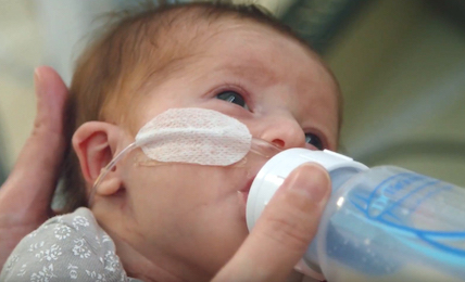 A baby receiving care at Johns Hopkins All Children's feeding from a baby bottle