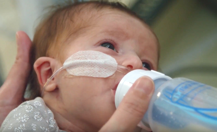 A baby receiving care at Johns Hopkins All Children's feeding from a baby bottle
