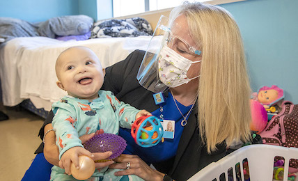K. Alicia Schulhof visits with young patient and family at Johns Hopkins All Children's Hospital