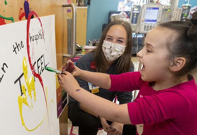 Maya paints with Child Life specialist Carli Fischer, M.S., CCLS. Fischer created the activity to help Maya express her feelings about being in the hospital.