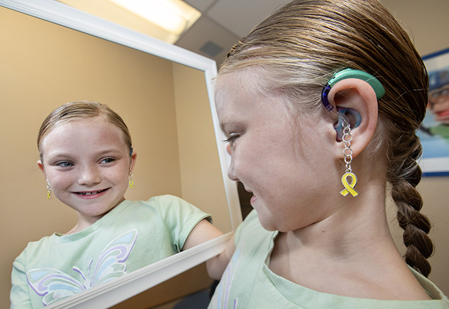 Audrey showing the jewelry she has made for hearing aids.