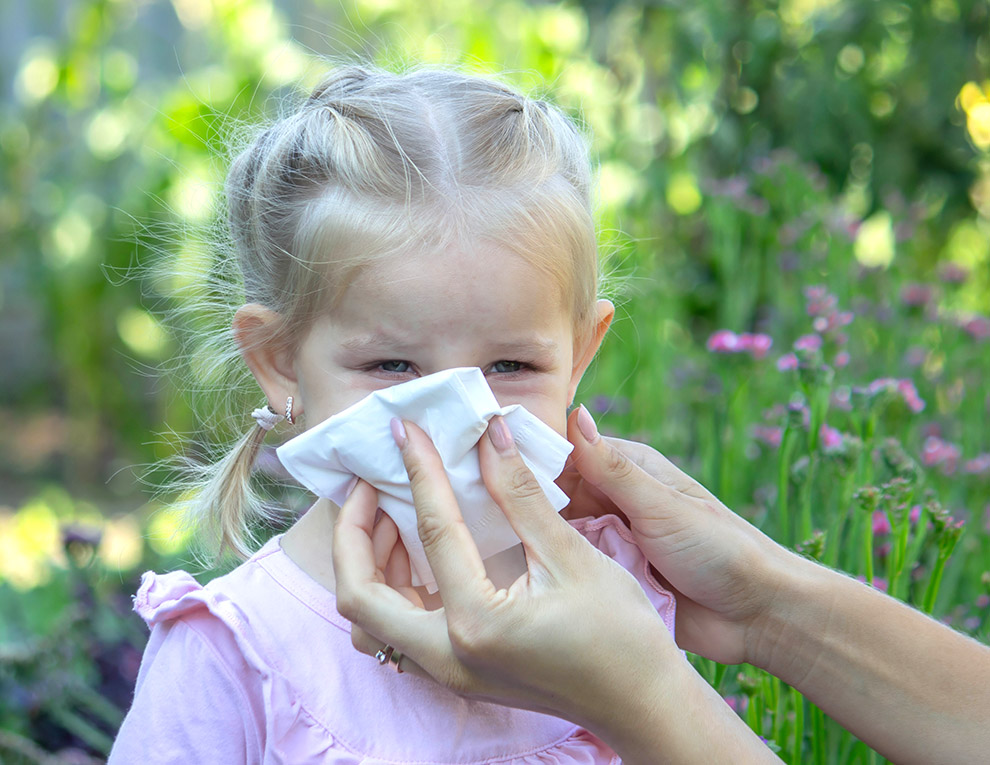 Image: A small girl getting help blowing her nose. 