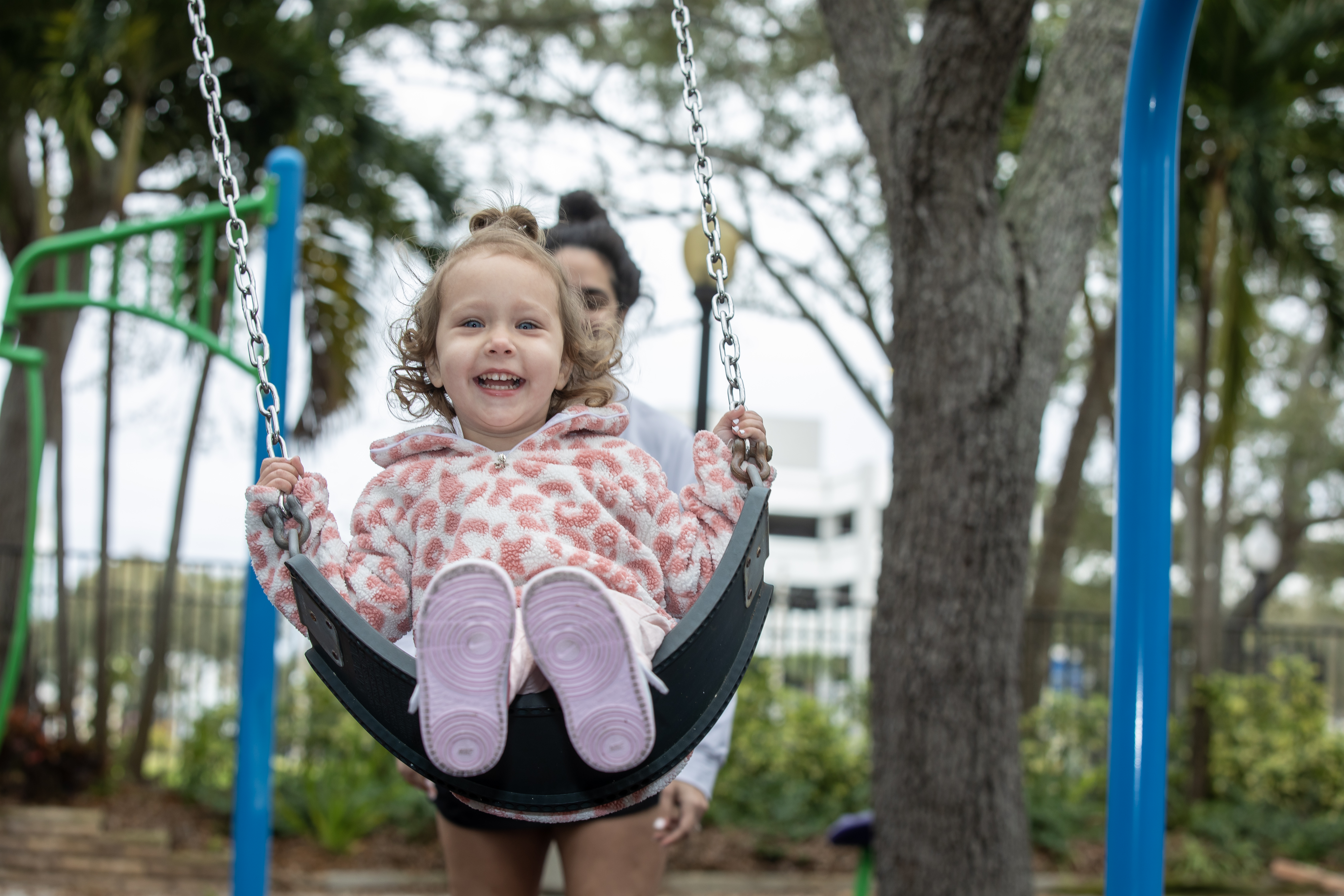 Heart patient Millie playing at a park outside on a swing.