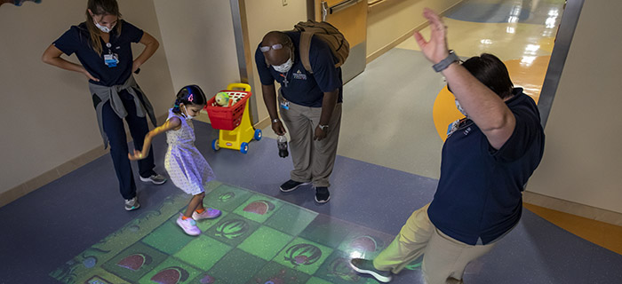 Little girl playing a game with an employee in a hallway of Johns Hopkins All Children's Hospital.