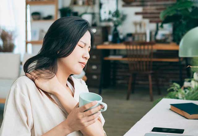 Woman experiencing neck pain while working from home