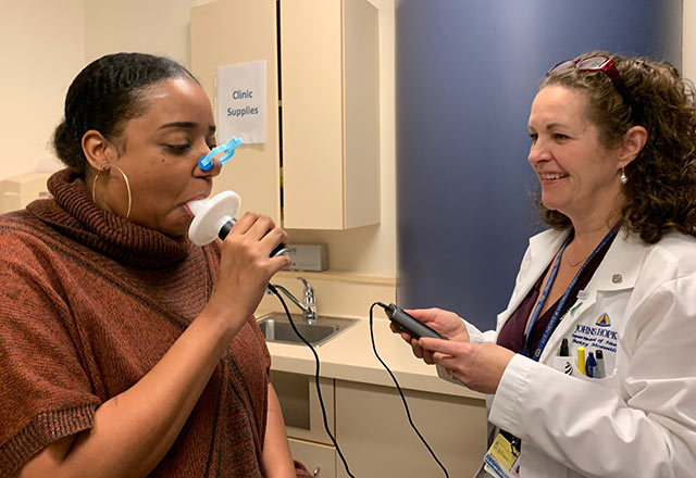 Betsy helping a patient use a spirometer 