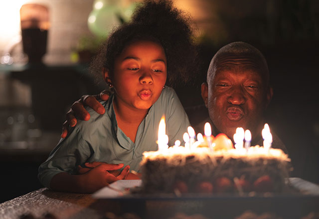 girl helps grandfather blow out birthday candles