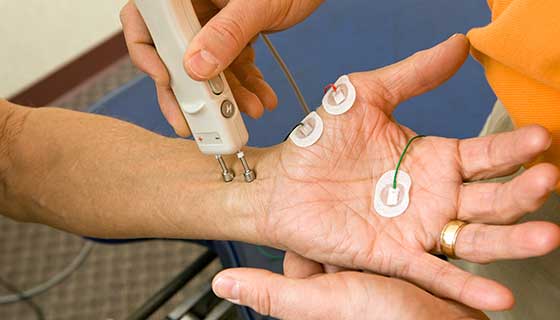 Patient with electrodes on the palm of their hand to measure nerve function