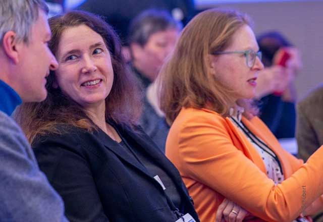 A diverse group of individuals seated at a conference table, engaged in discussion and collaboration.