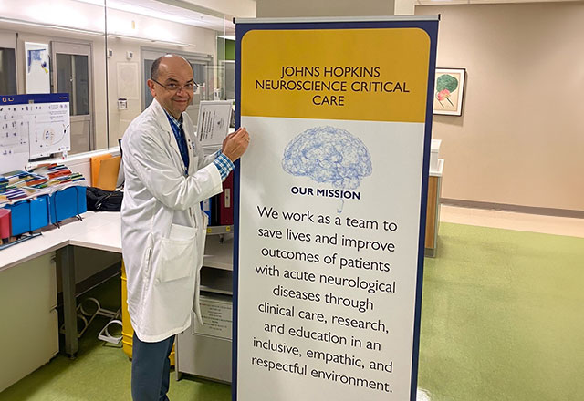 A Johns Hopkins clinician signing a large banner with the mission statement on it.