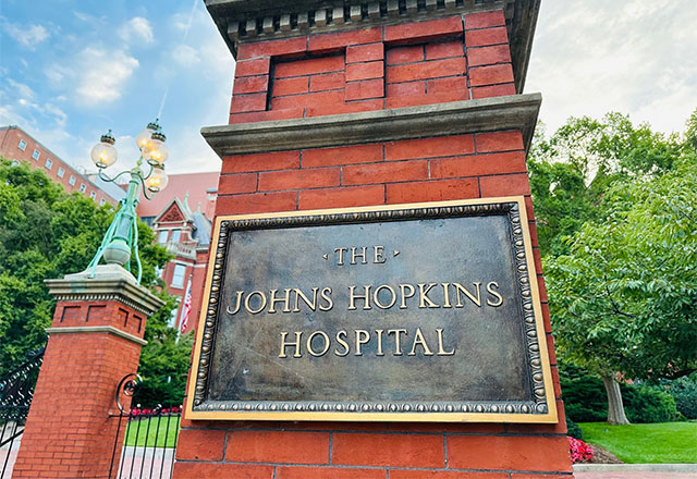 Picture of The Johns Hopkins Hospital sign on an old brick post.