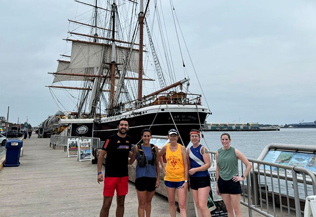 The Johns Hopkins NCCU group standing in front of a ship in a harbor.