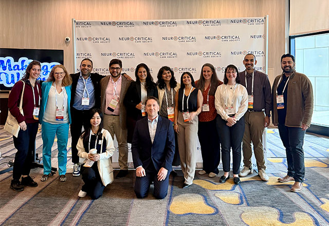 Members of Johns Hopkins standing in front of a Neurocritical Care Society banner for a photo op.