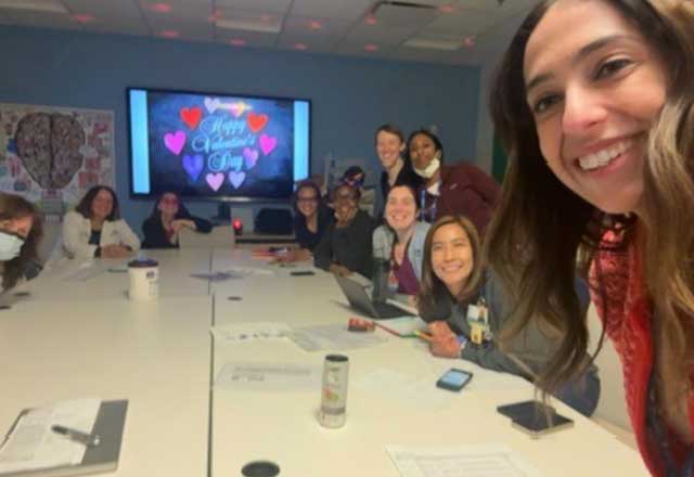 A group of smiling NCCU trainees sit around a conference table. A screen in the back displays "Happy Valentine's Day" with hearts, creating a cheerful atmosphere.