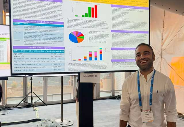 An NCCU fellow standing in front of a poster at a conference
