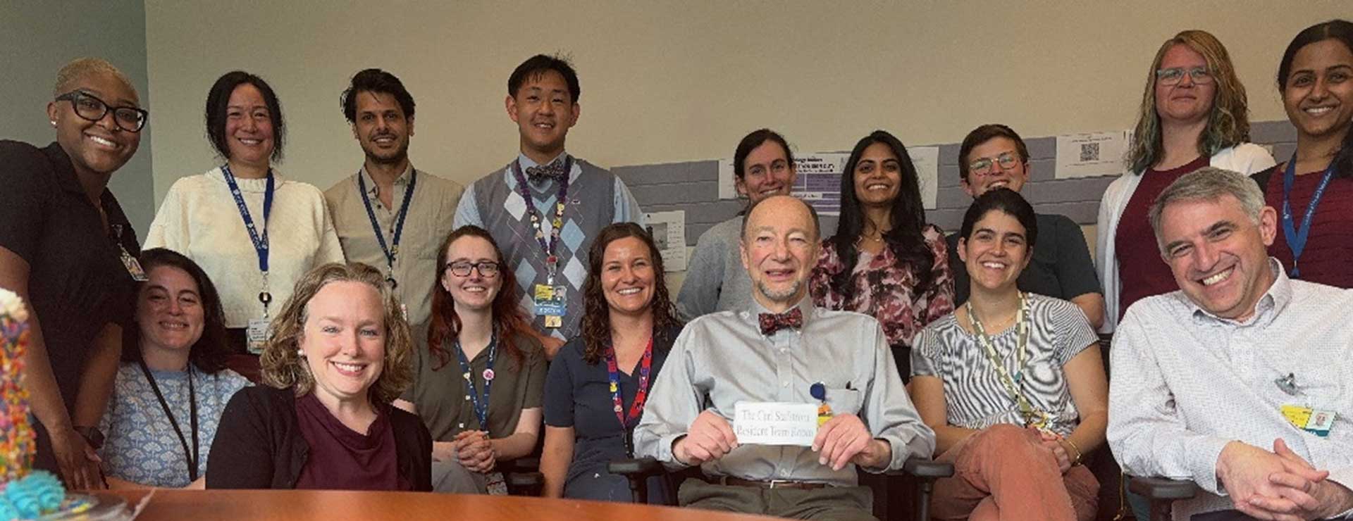 A group of Johns Hopkins pediatric neurology faculty and trainees sitting at the table and smiling.
