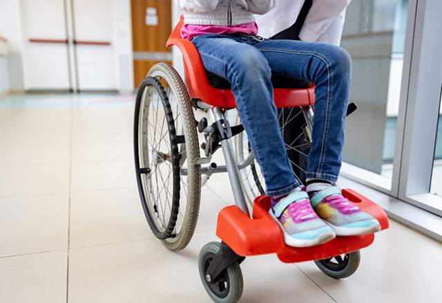 The legs of a child sitting in a wheelchair