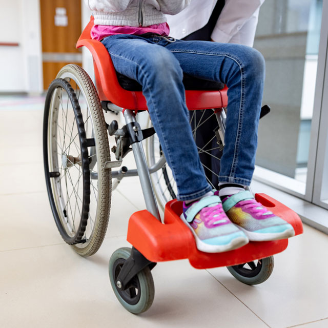 The legs of a child sitting in a wheelchair