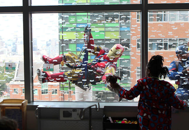window washers dressed as superheroes wave at children